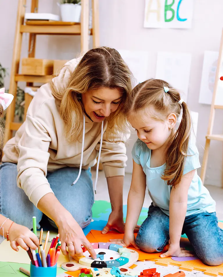 a nursery worker helping a child at preschool